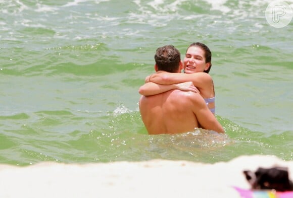 Cauã Reymond e Mariana Goldfarb se abraçam ao tomar banho de mar