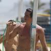 Márcio Garcia, de sunga, joga futevôlei na praia da Barra, no RJ, e se refresca tomando banho de balde e mangueira, em 3 de março de 2013