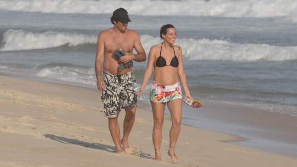 Luciano Szafir passeia com a mulher, que exibe barriga de grávida em praia
