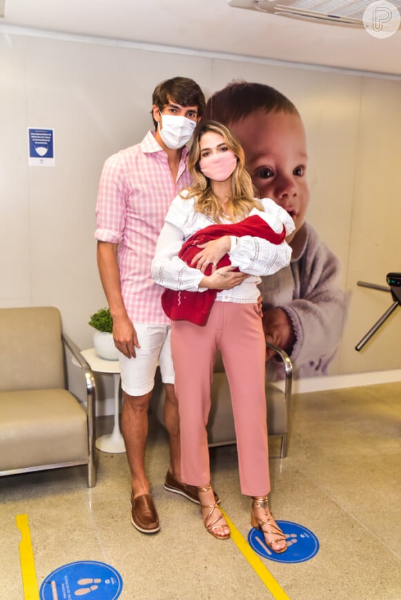 Kaká usa blusa rosa e short branco enquanto Carol Dias aposta em blusa branca e calça rosa na saída da maternidade