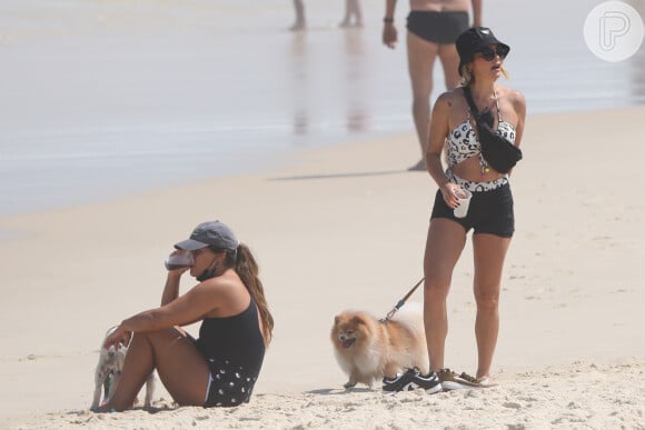 Flávia Alessandra e Giulia Costa escolhem maiôs com recortes para passear na praia com os cachorros