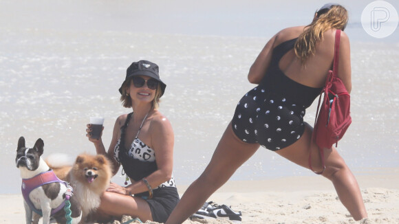 Flávia Alessandra e Giulia Costa usam maiôs com recortes para passear na praia com pets