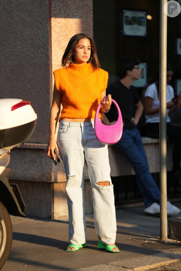 Minimalista, bolsa Swipe Bag aparece com jeans e blusa laranja em look