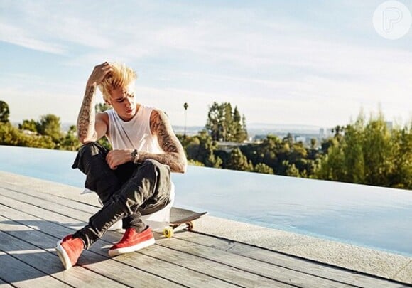 Justin Bieber posa sentado em um skate