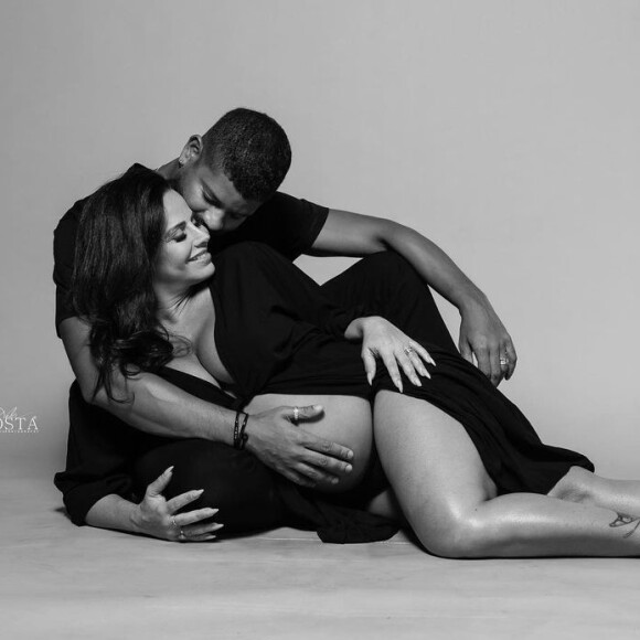 No clique, Viviane Araújo usa um hobby preto e mostra o barrigão ao lado do marido, Guilherme Militão