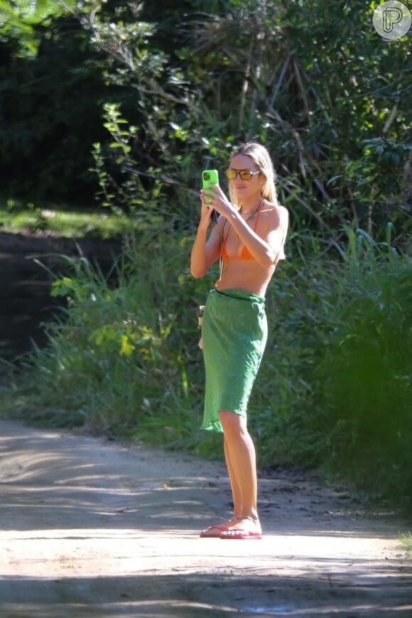 Biquíni laranja de Candice Swanepoel: peça de beachwear foi combinada com saída de praia em verde pela modelo