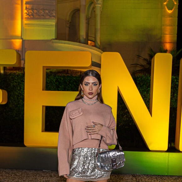 O look usado por Jade Picon combina botas de cano alto, suéter com minibolsa e saia com brilho