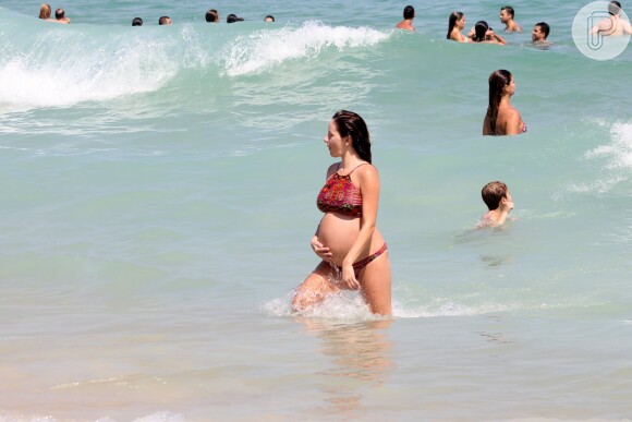Erika Mader acariciou sua barriga enquanto tomou um banho de mar