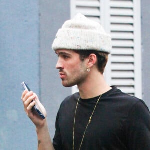 João Guilherme apareceu falando ao celular usando uma touca branca, blusa preta, calça alfaiataria xadrez e botas de cowboy no Rio