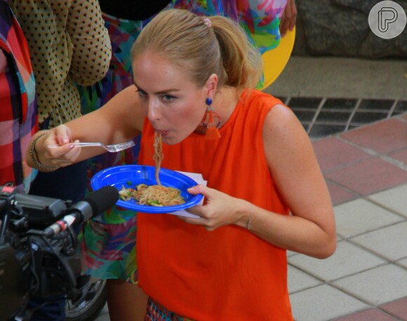 Angélica come yakisoba em prato de plástico durante gravação do programa 'Estrelas'