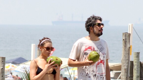 Bruna Linzmeyer e o marido tomam água de coco enquanto se exercitam em praia