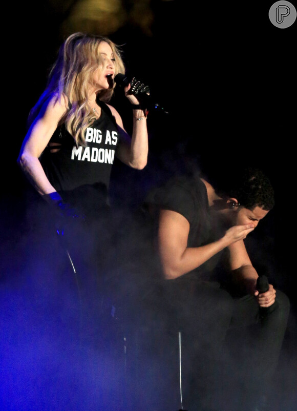 Madonna se apresenta de surpresa com rapper no Coachella, o beija e deixa músico de cara feia, com mão na boca. Grillz nos dentes da artista pode ter atrapalhado o beijo