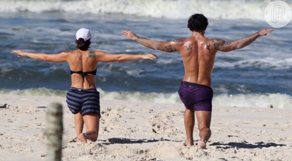 Juliano Cazarré se exercita com a mulher em praia carioca