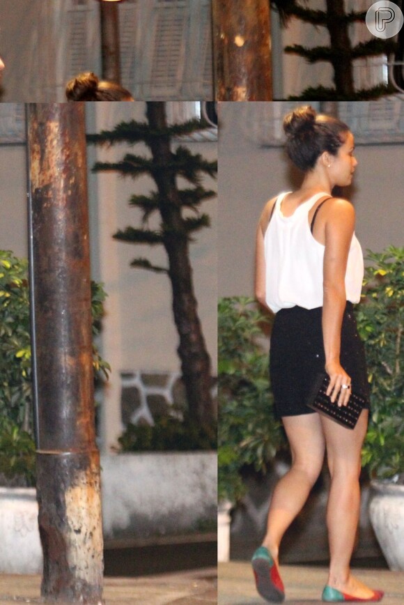 A atriz Nanda Costa usa minissaia preta, blusa branca e sapatilhas coloridas
