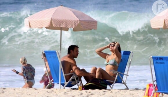 Priscila Fantin pega um solzinho enquanto o marido, Renan Abreu, se protege sob a barraca na praia do Leblon, RJ