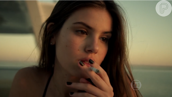 Após matar o amante, Angel (Camila Queiroz) fuma um cigarro e mostra frieza, antes de chamar por socorro
