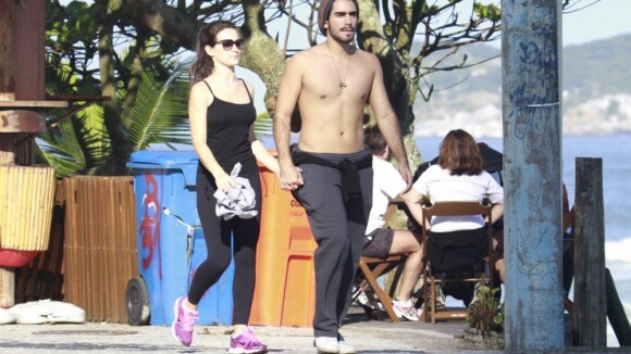Bianca Bin caminha com o marido, Pedro Brandão, na orla da praia da Barra