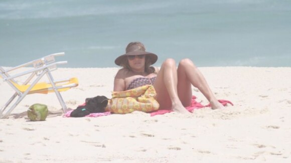Christine Fernandes lê revista e mostra boa forma em praia carioca