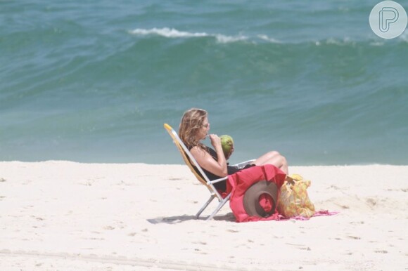 Christine Fernandes bebe água de coco na praia
