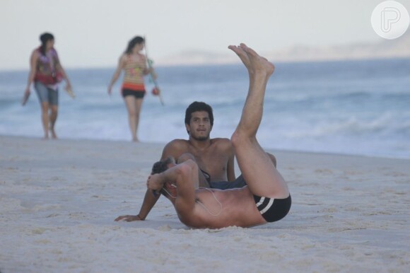Marcello Novaes é observado pelo filho, Diogo, enquanto faz uma sequência de abdominais na areia da praia da Barra da Tijuca, Zona Oeste do Rio de Janeiro