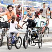 Carolina Kasting passeia de bicicleta triciclo na praia com o marido e a filha