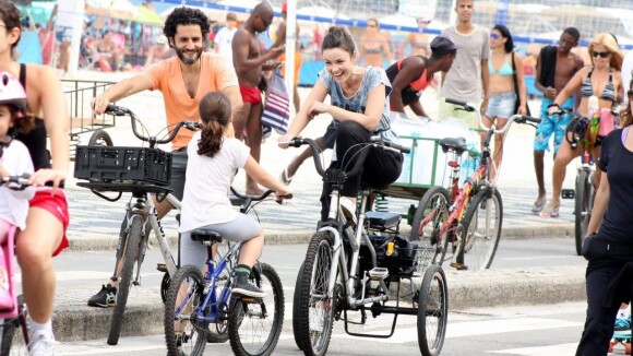 Carolina Kasting passeia de bicicleta triciclo na praia com o marido e a filha
