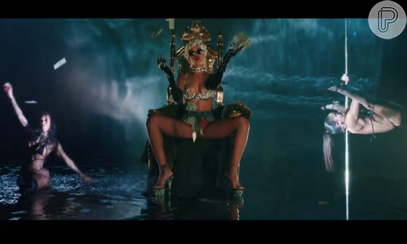 Rihanna é cercada por strippers, ora no pole dance ora fazendo danças sensuais enquanto distribui dinheiro em 'Pour It Up'
