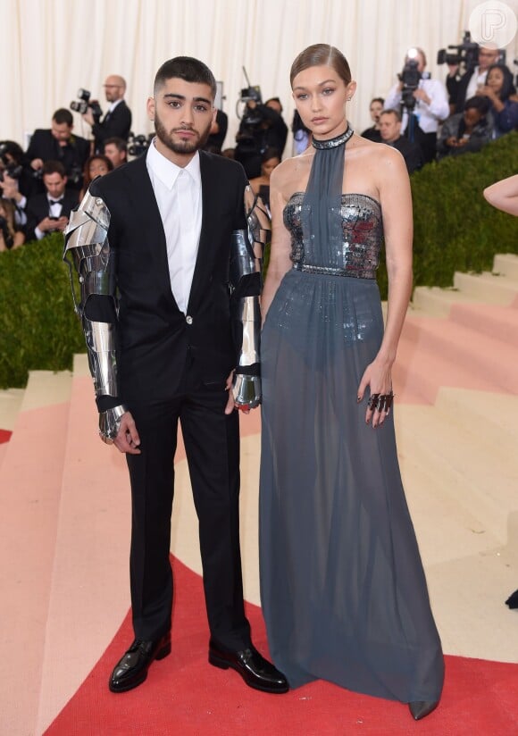 O casal Gigi Hadid e Zayn Malik chegou junto ao Met Gala. Ela apostou em vestido Tommy Hilfiger e ele em terno Versace preto com braços de metal adornados com cristais Swarovski e detalhes Medusa