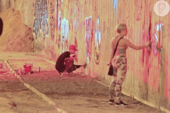 Justin Bieber grafita muro acompanhado de amiga
