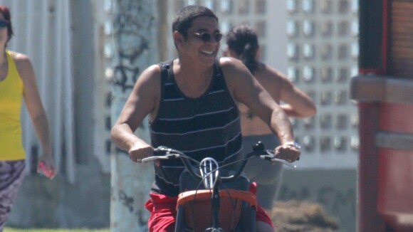 Zeca Pagodinho acena para fotógrafo durante passeio de bicicleta em praia, no RJ