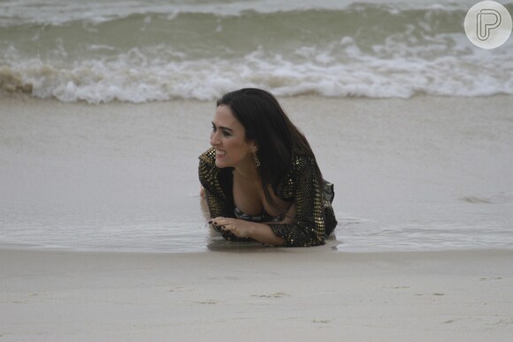 A atriz faz pose deitada na areia como se estivesse realizando um clipe