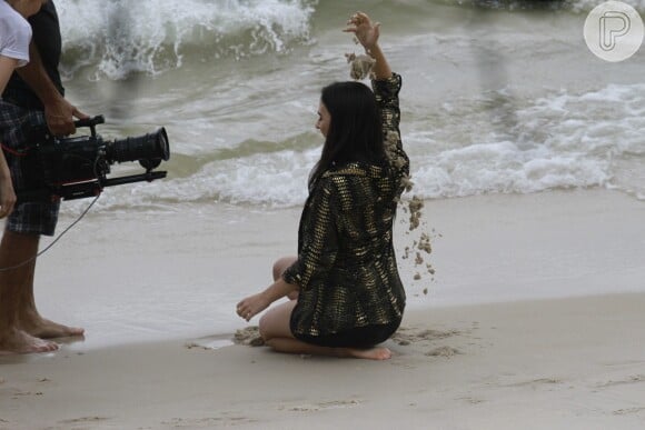 A atriz brinca com a areia da praia