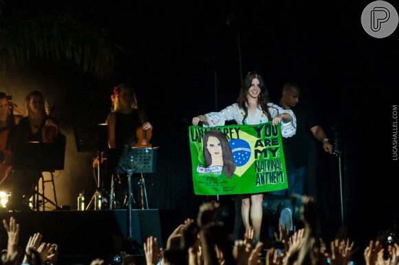 Lana Del Rey ficou feliz com uma bandeira personalizada do Brasil que ganhou de um fã durante o show em Belo Horizonte