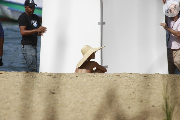 Cansada, Rihanna aproveitou uma rápida pausa para se sentar na areia
