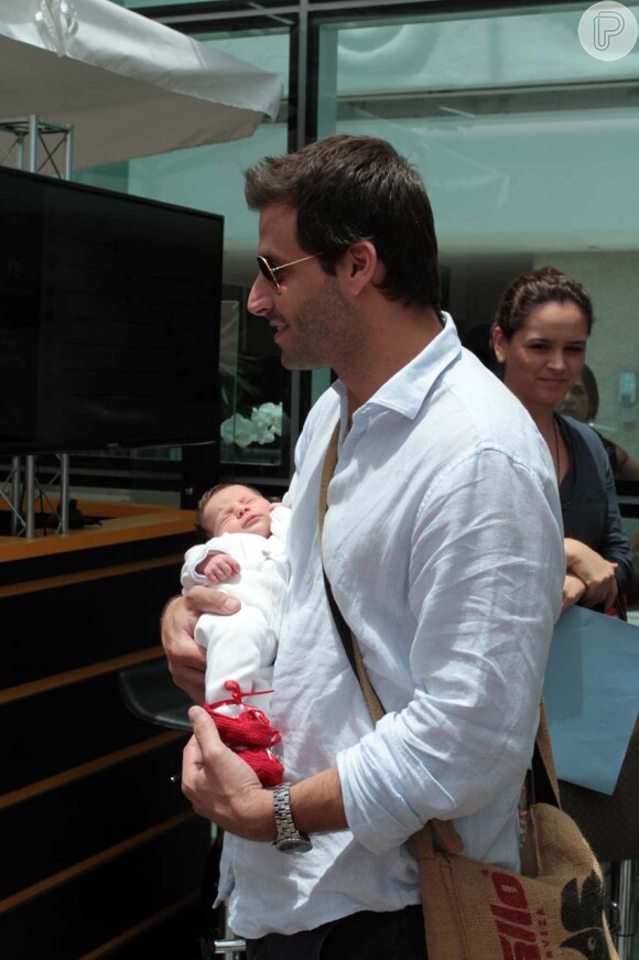 Henri Castelli segura a filha nos braços na saída do hospital, em São Paulo