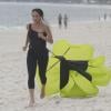  A atriz corre na areia com um paraquedas amarrado em sua cintura