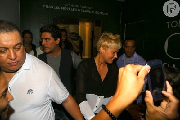 Xuxa dá atenção aos fãs enquanto o namorado a escolta