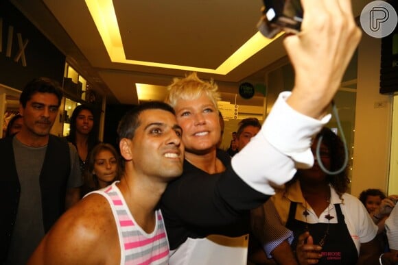Xuxa faz selfie com um fã e Junno os observa ao longe