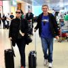 Serginho Groisman caminha sorridente pelo aeroporto com a mulher, Fernanda Molina