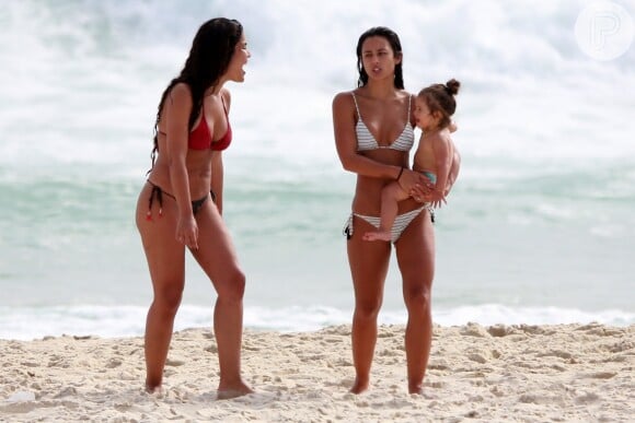 Yanna Lavigne caminha na areia com a filha, Madalena, no colo