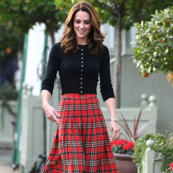 Kate Middleton combinou a saia xadrez midi e plissada com botas e cardigã preto