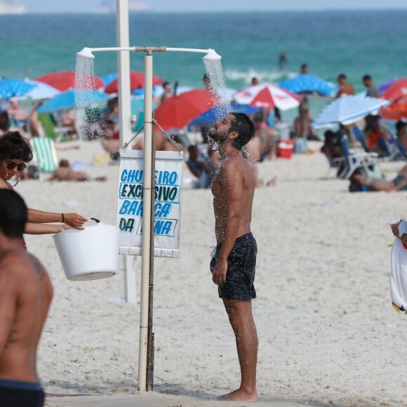 Após deixar o mar, Rodrigo Simas se molhou em chuveiro na areia observado por Agatha Moreira
