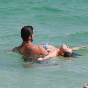 Rodrigo Simas segura Agatha Moreira dentro do mar enquanto a atriz boia na água