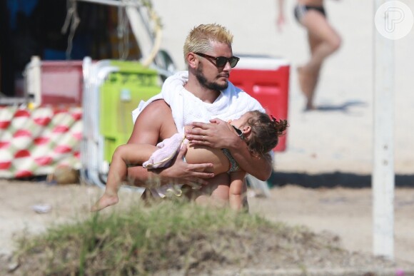 Bruno Gissoni segura a filha no colo enquanto a menina dorme tranquilamente