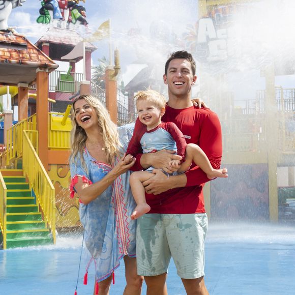 Karina Bacchi e Amaury Nunes posam sorridentes com Enrico em parque aquático