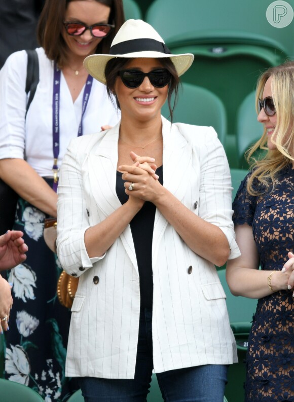 Meghan Markle faz anisversário neste domingo (4 de agosto de 2019).  Meghan assistiu a amiga Serena Williams em Wimbledon (em julho de 2019): o look incuía jeans, t-shirt preta e chapéu panamá, mas o que chamou a atenção foi o cordão em ouro com a letra 'A', de Archie