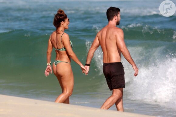 Juliana Paes e o marido, Carlos Eduardo Baptista, andam de mãos dadas na praia