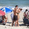 Juliana Paes e o marido, Carlos Eduardo Baptista, se abraçam em praia do Rio enquanto filhos brincam