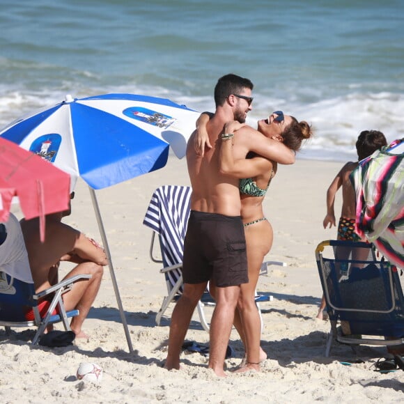 Juliana Paes e o marido, Carlos Eduardo Baptista, se abraçam em praia do Rio enquanto filhos brincam