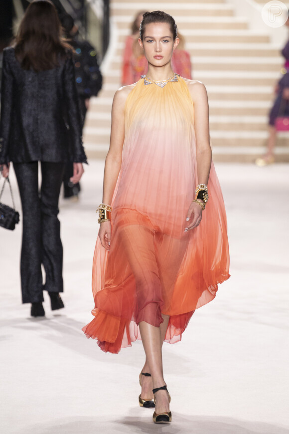 A Chanel também apresentou looks solares, como o vestido plissado em degradê de amarelo e coral
